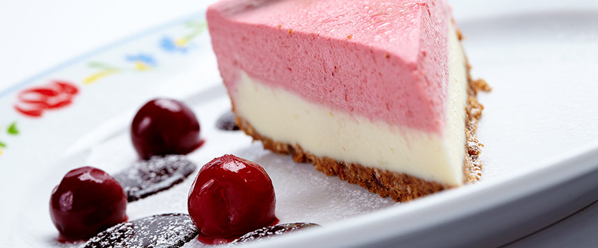 Portion of cake with strawberry mousse and candied cherries: desserts with preserved fruit are delicious.